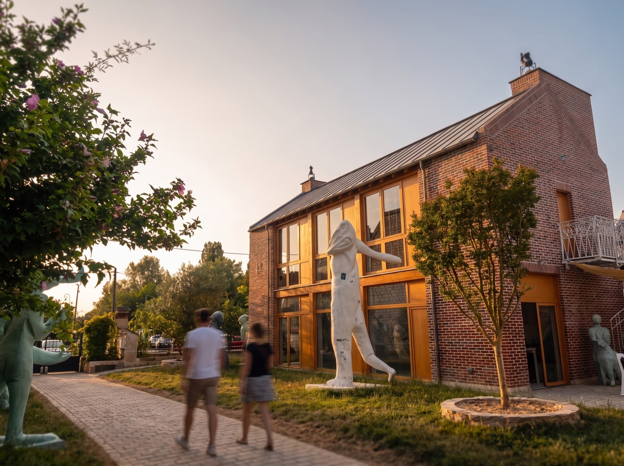 Le LabMusée à l'heure dorée, ses sculptures monumentales et des visiteurs dans le jardin